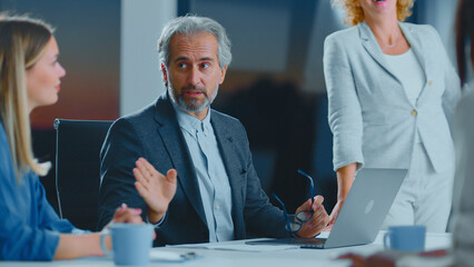 Business colleagues collaborating around a table in a modern office, exchanging ideas and gesturing during a focused meeting that shows teamwork and active discussion