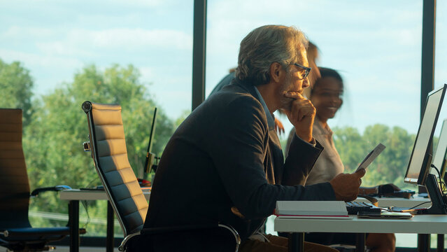 Business colleagues working together at computer workstations in a contemporary office setting, focusing on tasks and interacting in a dynamic corporate environment - Powered by Adobe