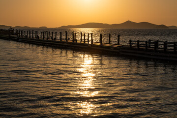 Fototapeta premium pier silhouette on the sunlight-reflecting sea during sunset