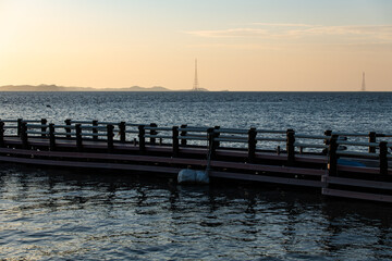 Obraz premium idyllic seascape with island, pylon and pier during sunset
