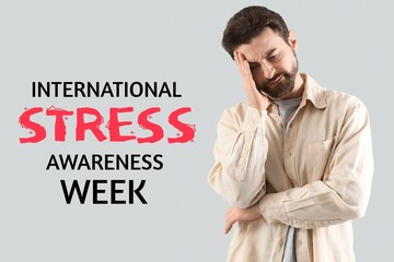 Worried young man on grey  background. International Stress Awareness Week