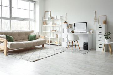 Interior of light living room with sofa, shelf unit and workplace