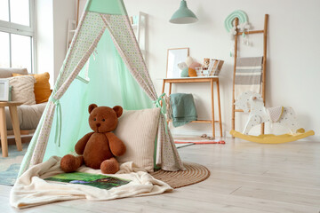 Play tent with toy bear and book in living room © Pixel-Shot