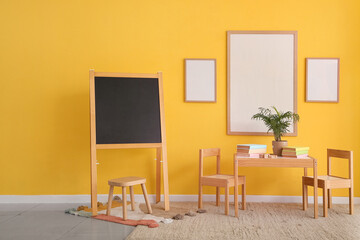 Interior of children's room with blank frames, chalkboard and table