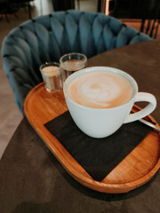 Creamy cappuccino resting on wooden tray in cozy cafe