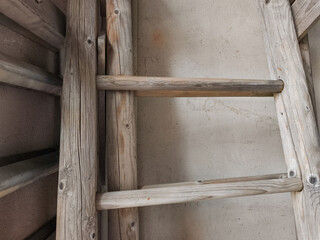 Old wooden ladders leaning against concrete wall