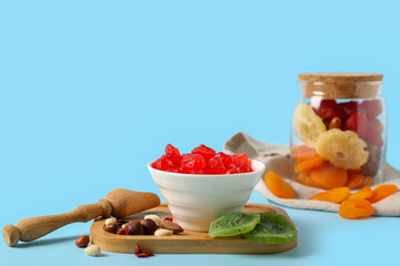 Bowl with candied cherries, kiwi and different nuts on blue background