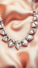 Obraz premium Close up of sparkling diamond necklace featuring teardrop and oval cut stones on soft pink satin fabric