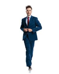 happy proud businessman smiling and buttoning navy blue suit while walking