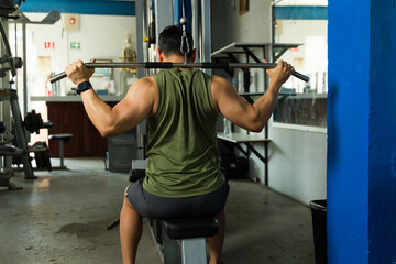 Strong man doing lat pulldown exercise in gym for strength training