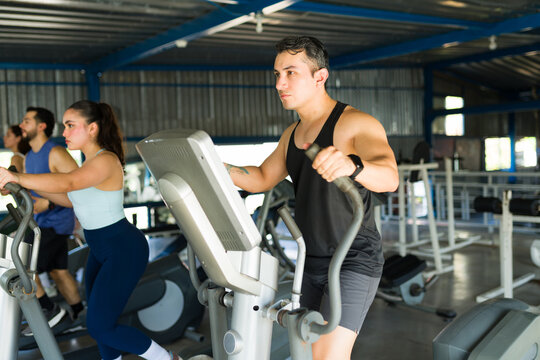 People training on elliptical trainers in gym - Powered by Adobe