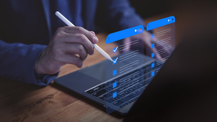 Businessman using digital checklist interface on laptop with pen, illustrating modern task...