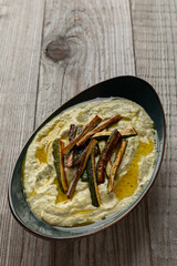 Courgette and tahini dip with fried zucchini strips on top. Rustic wooden background with copy space.