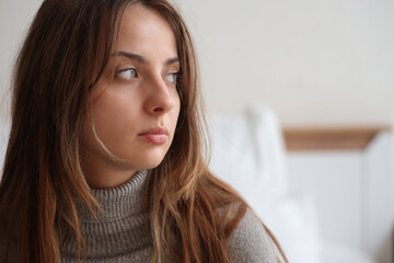 Sad young woman in bedroom, closeup