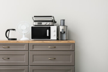 Different modern household appliances on counter against white wall