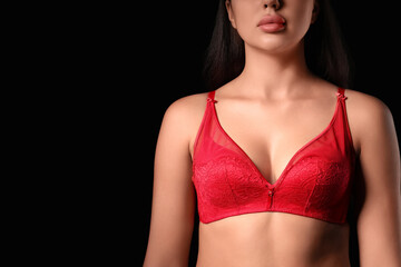 Fototapeta premium Beautiful young woman in red lace bra on dark background
