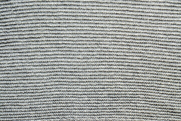 Horizontal ribbed knit texture in grey tones creating striped pattern effect for background use. Garter stitch detail, uniform knitting rows, monochrome textile surface, structured fabric pattern.