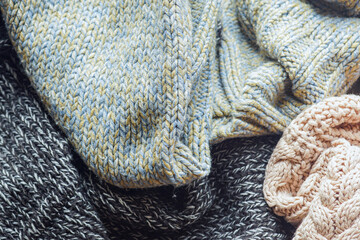 Close-up of cable knit sweaters showing texture patterns and folds. Handcrafted knitwear detailю Concepts of chunky knit design, warm winter clothing, cozy garment collection, and quality wool fabric.