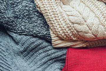 Woolen fabric of different colors and knitting techniques folded next to each other. Symbol of autumn and winter cozy warm outfits. Durable wardrobe investment and practical style foundation.