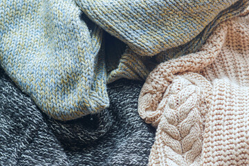 A close-up of jumpers in various colors and knitting techniques. Concepts of winter wellness essentials, self-care comfort items and relaxation wardrobe components. Symbol of cozy home atmosphere.