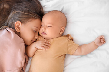 Cute little girl with her baby brother sleeping on bed, top view