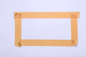 Frame made of brown masking tape strips on white background