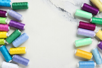 Frame made of colorful thread spools on marble background