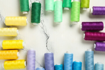 Frame made of colorful thread spools on marble background