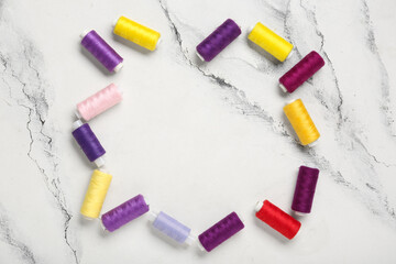 Frame made of colorful thread spools on marble background