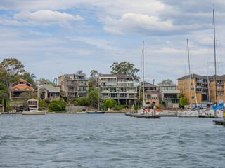 Fototapeta premium Residential Houses and apartment buildings on Parramatta River Sydney Harbour on a warm spring cloudy overcast day in Sydney NSW Australia