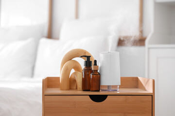 Air humidifier with essential oils and decor on table in bedroom
