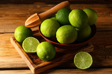 Bowl and board with fresh ripe limes on wooden background