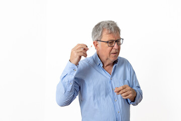 sixty years old man with blue shirt inserting his hearing aid