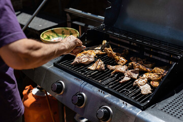 Man grilling tasty chicken on outdoor barbecue for summer party, preparing delicious food for friends and family, enjoying a sunny afternoon cooking outdoors