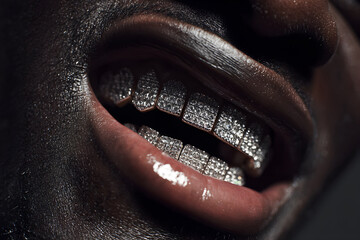 Close-up of a black man&rsquo;s smiling mouth wearing diamond-encrusted grillz with dramatic lighting