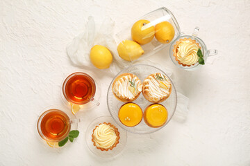 Tasty lemon desserts with tea on white grunge background