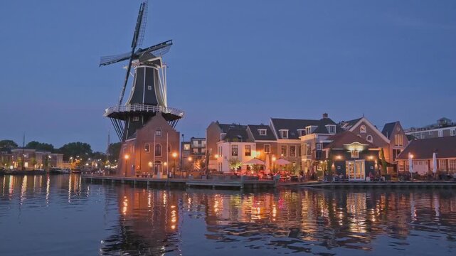 Golden lights illuminate Windmill De Adriaan along the Spaarne River at dusk in Haarlem.