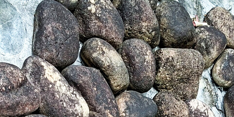 Close Up Of A Textured Wall Constructed From Rounded Dark Grey And Brown River Stones