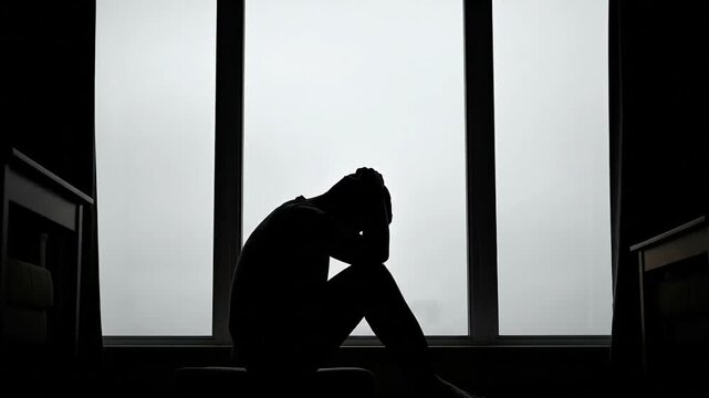 Silhouette of depressed man holding head conveys mental health issues