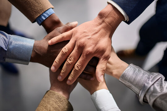 Team showing unity by stacking hands together in office