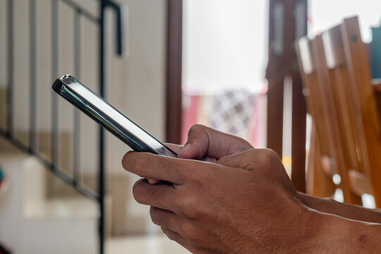 A man's hand typing a message on his smartphone at home