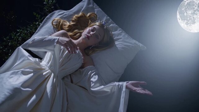 Femme endormie sous la pleine lune dans une lumi&egrave;re bleut&eacute;e