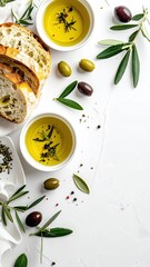 Artistic arrangement of fresh olive oil bread olives and herbs on a white surface.