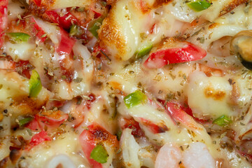 Close-up macro photo of seafood pizza topped with shrimp, squid, and melted cheese, showing rich texture and vibrant color in delicious detail.