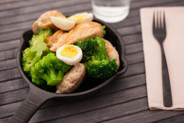 chicken breast with broccoli and quail eggs in small cast iron skillet