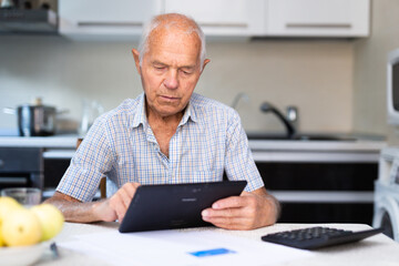 Elderly man using digital tablet to shop online from home