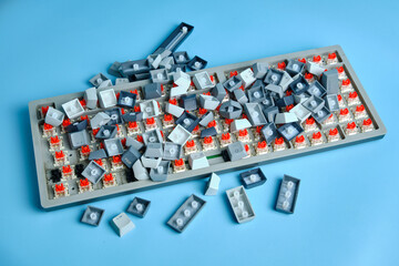 Disassembled Mechanical Keyboard With Gray And Blue Keys on a Tray, Red Switches Scattered Across a Blue Background