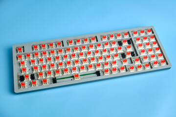 Disassembled Mechanical Keyboard With Red Switches on Blue Background for Repair or DIY Projects