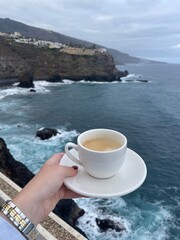 Coffee cup with scenic ocean and cliffside backdrop. Calm seaside morning, travel and slow living inspiration.