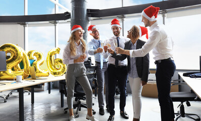 Business people are celebrating holiday in modern office drinking champagne and having fun in coworking. Merry Christmas and Happy New Year 2026